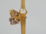 a gold watch with a dragon on it on a stand