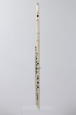 a silver flute on a clear stand against a gray background