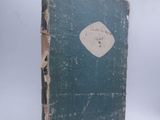 an old book with a blue cover sitting on a white surface