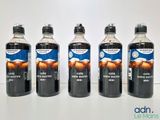 Quatre bouteilles de soda sont posées sur une table devant un fond blanc