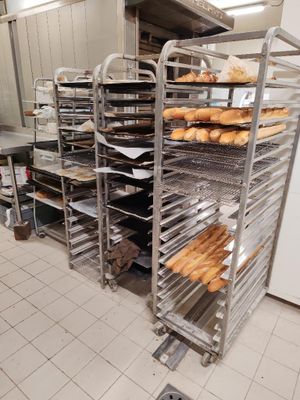de nombreux plateaux de pain posés sur une étagère dans la cuisine