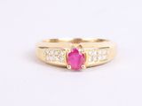 a close up of a gold ring with a ruby stone and diamonds