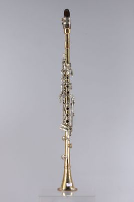 a close up of a silver and gold clarinet on a stand