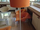 des chaises orange et une table dans un salon où se trouve un grand lampadaire