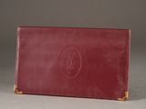 un vieux portefeuille en cuir rouge avec un monogramme sur le devant