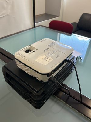 un ordinateur portable posé sur une pile de livres, sur une table en verre