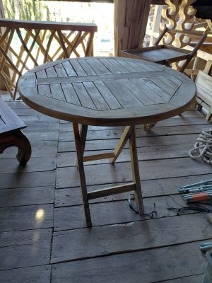 a wooden table and chairs on the porch of a house