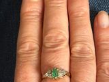 a woman ' s hand with a ring on it that has a green stone on it