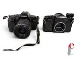 two cameras sitting next to each other on a white surface