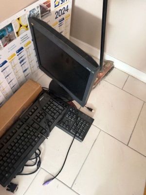 un ordinateur et un clavier posés par terre à côté d'un carton