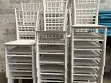 Plusieurs chaises blanches sont empilées les unes sur les autres devant un mur.