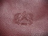 a close up of a red leather bag with a small emblem on it