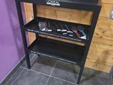 une étagère noire sur laquelle sont posés des outils, dans un coin de la pièce