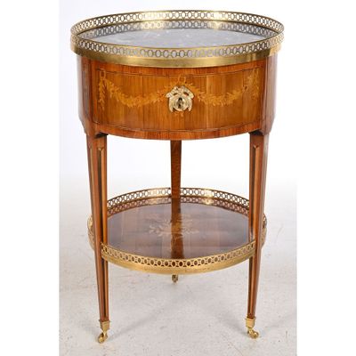 une table d'appoint avec un plateau en verre et une plaque en laiton sur le dessus