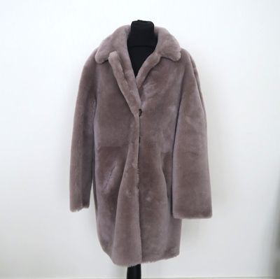 le manteau est posé sur un mannequin devant un mur blanc