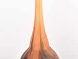 un vase noir et orange posé sur une surface blanche