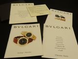 three brochures of bulgari watches on display on a table