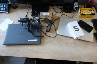 a desk with a laptop, phone, and other electronics on it