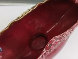 a red bowl with a gold decoration on it