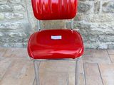 a red chair sitting on a brick floor next to a stone wall