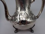 a silver tea pot with a handle on a table