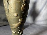 a bronze vase sitting on top of a wooden base