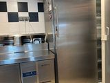 réfrigérateur et congélateur en acier inoxydable dans une cuisine professionnelle aux murs à carreaux