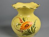 a yellow vase with flowers painted on it