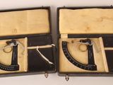 une paire d'anciens outils noirs et blancs dans un étui posé sur une surface blanche