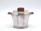 a silver pot with a wooden handle on a white surface