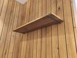 a wooden shelf on the wall in the corner of the room