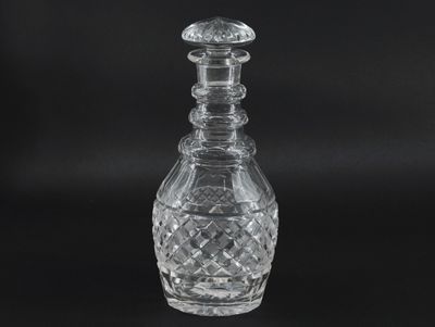 a clear glass decanter with a stopper on a black background