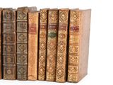 several old books are lined up in a row on a white surface