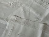 un drap blanc orné de motifs brodés, posé sur un lit