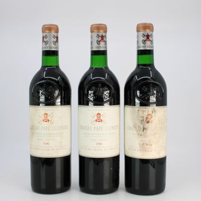 three bottles of red wine sitting next to each other on a white surface