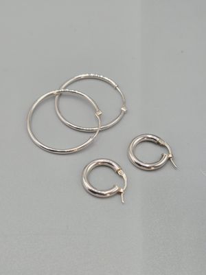 un lot de trois boucles d'oreilles en argent en forme d'anneaux posé sur une table