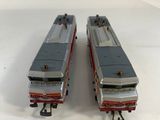 two toy trains sitting side by side on a white surface