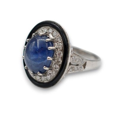 gros plan d'une bague avec une pierre bleue entourée de diamants