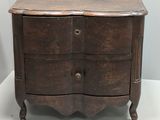 une petite commode en bois posée sur une surface blanche
