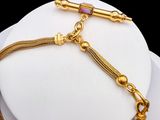 a close up of a gold chain bracelet on a white mannequin