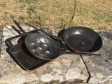 des casseroles et des poêles posées sur une dalle de pierre à l'extérieur, par une journée ensoleillée