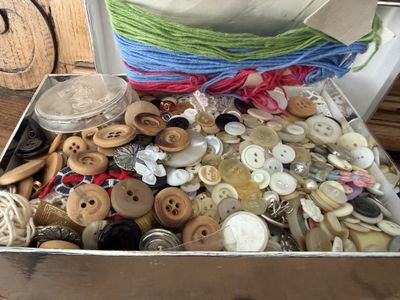 une boîte remplie de boutons et de fil posée sur une table