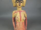 une vieille statue en bois représentant une femme coiffée d'un chapeau