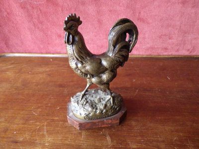 a bronze statue of a rooster on a wooden table