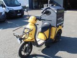 a yellow scooter parked in a parking lot with other vehicles in the background