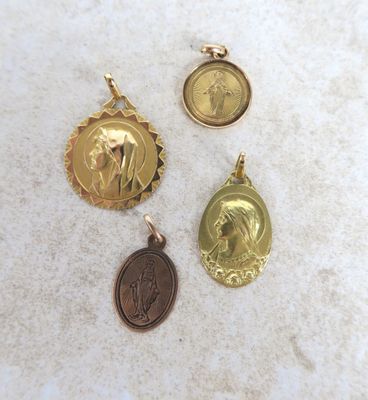 trois médailles d'or représentant Jésus et Marie sur un socle en marbre