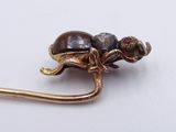 a gold brooch with a turtle on it on a white surface