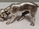 une figurine en argent représentant un chien, posée sur un fond blanc