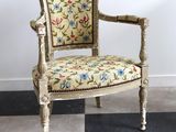 une chaise dont l'assise est recouverte d'un tissu à motifs floraux, posée sur un sol à carreaux noirs et blancs