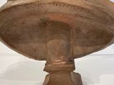 statue of a woman sitting on a pedestal with her hands on her head